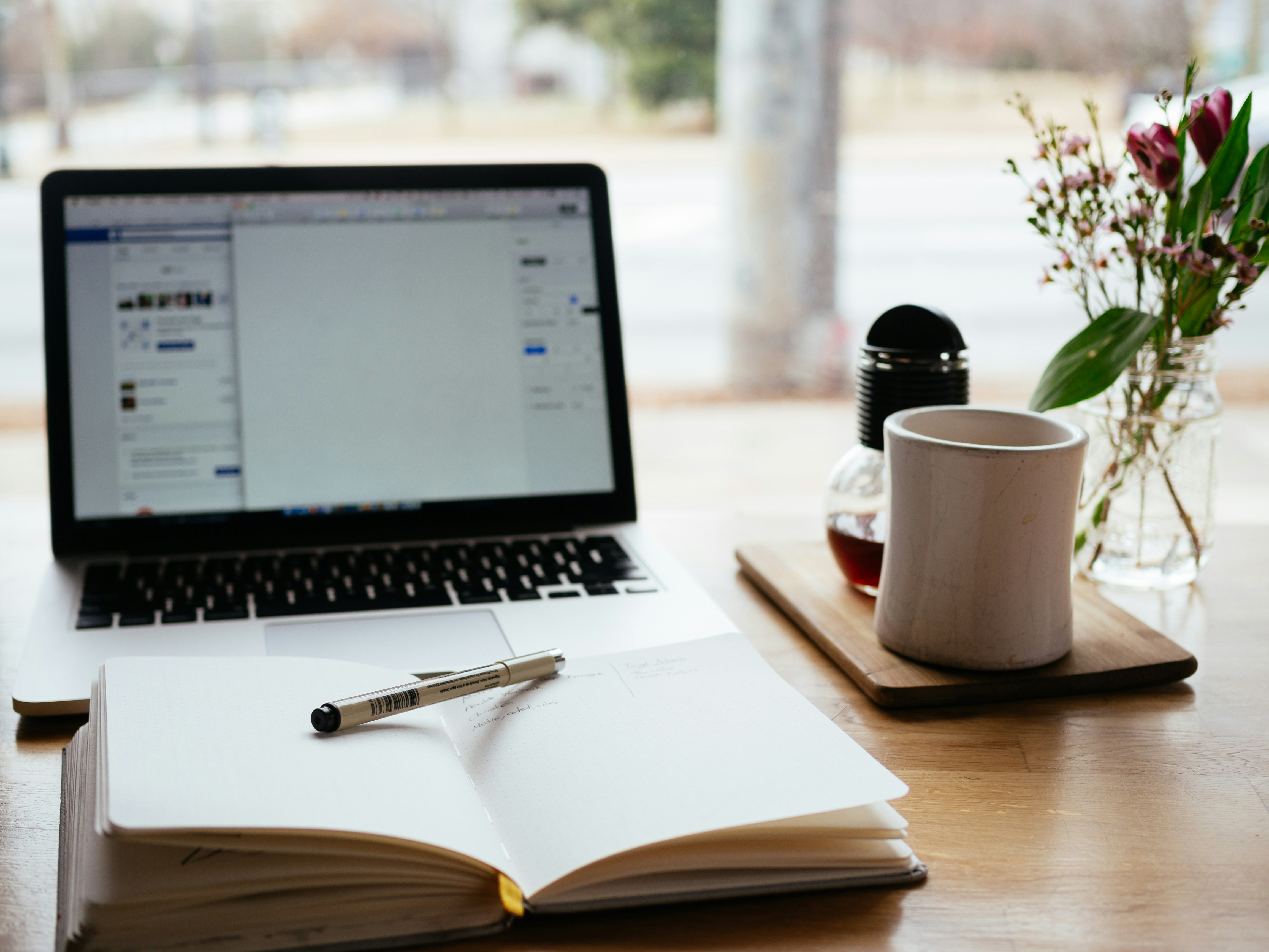 A notebook with a pen and a pencil and a laptop